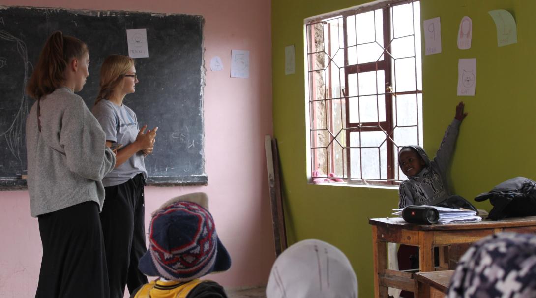 Two gap semester students teach a group of young children in Tanzania.