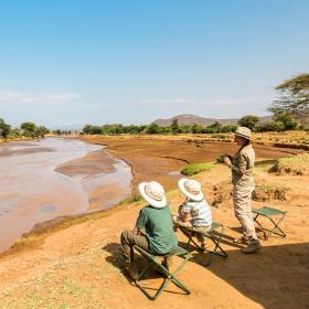 Adventurers look out over a waterhole while on safari during their Discovery Tour in Kenya.