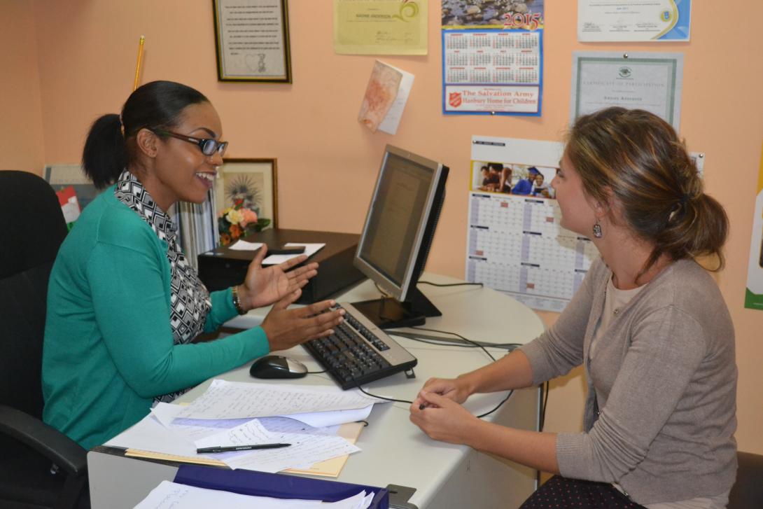 In a small office, a student doing a Psychology internship abroad has a friendly chat with a member of staff in Jamaica.