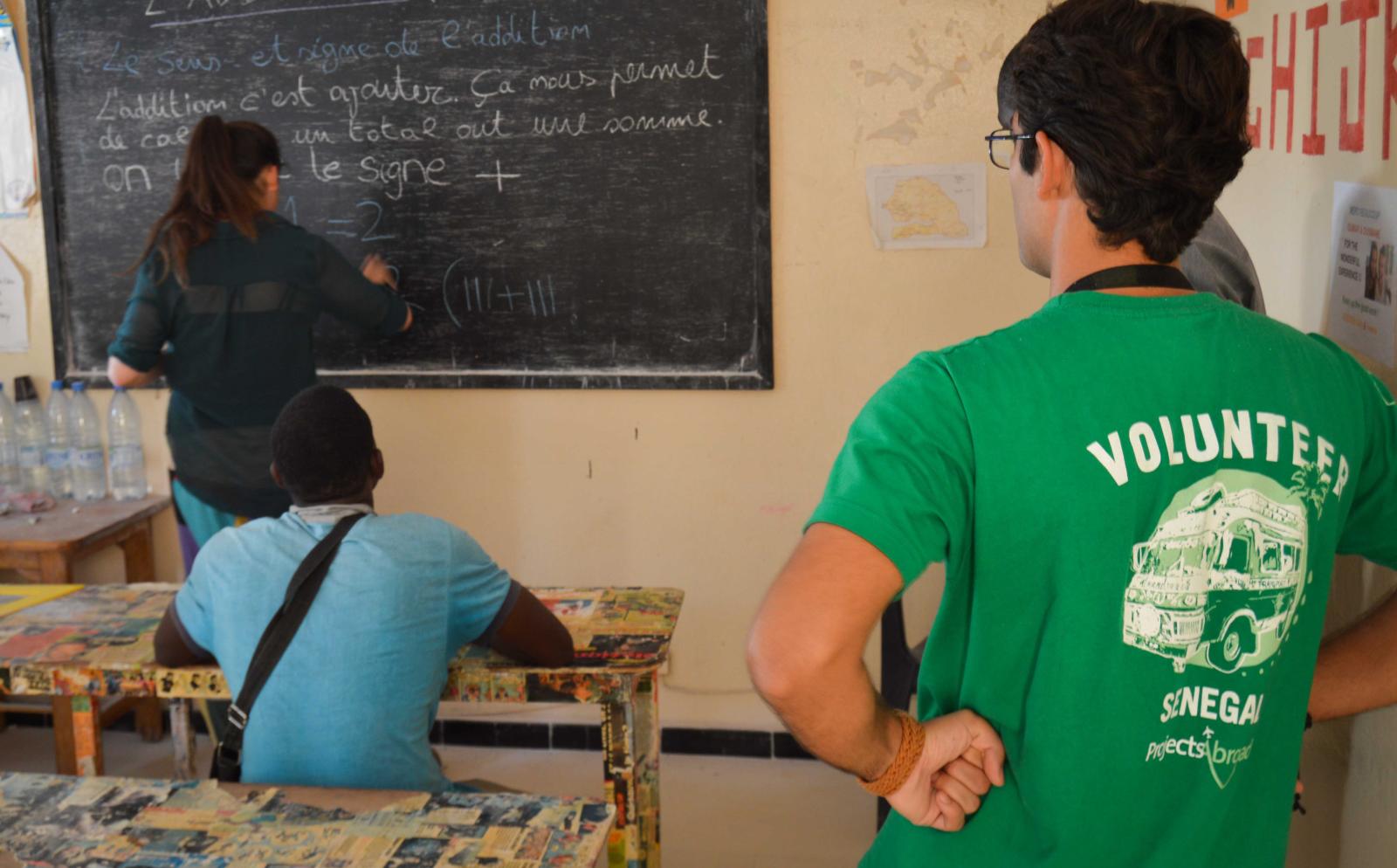 Projects Abroad volunteers provide a local business owner with math lessons in Senegal