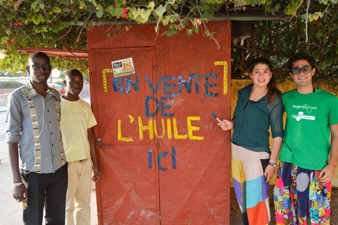 Two volunteers on a Micro-finance volunteer opportunity abroad with the stall that they helped a beneficiary open in Senegal. 