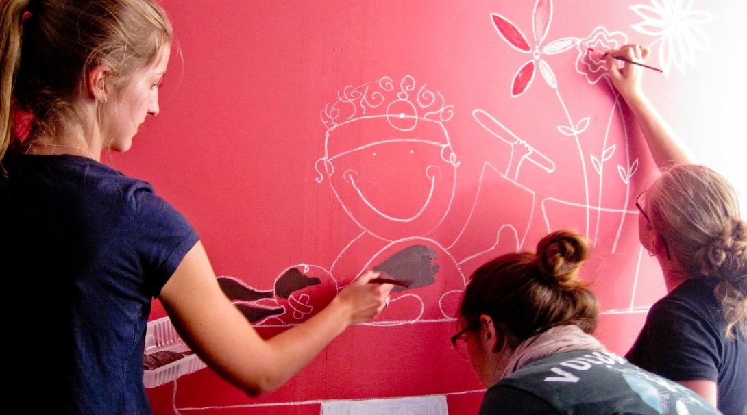 Projects Abroad Childcare volunteers help paint an educational mural on a wall at a care centre in Argentina.