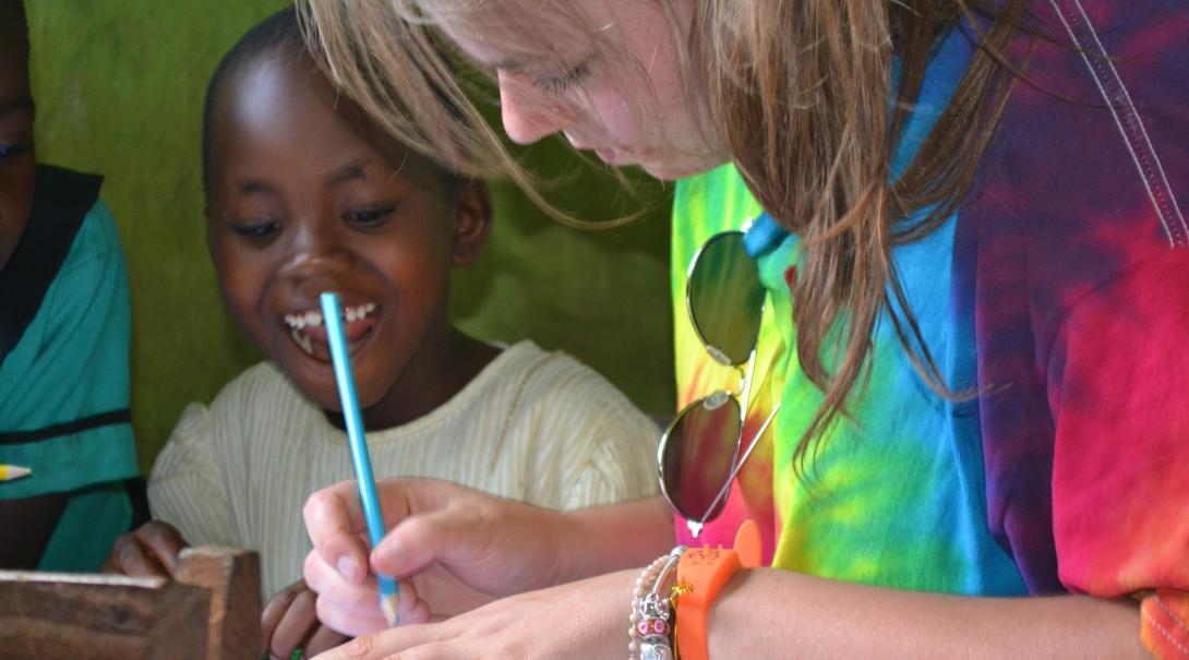 A child listens to a Childcare volunteer explain an English writing activity at a school in Ghana.