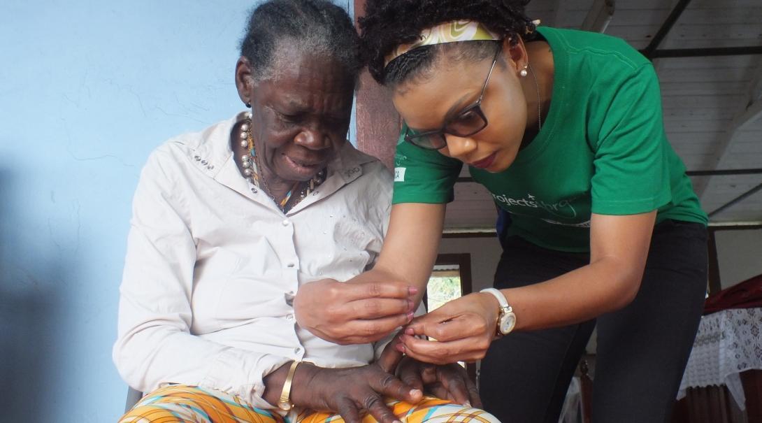 Projects Abroad volunteer helps an elderly woman with personal care during an outreach in Jamaica. 