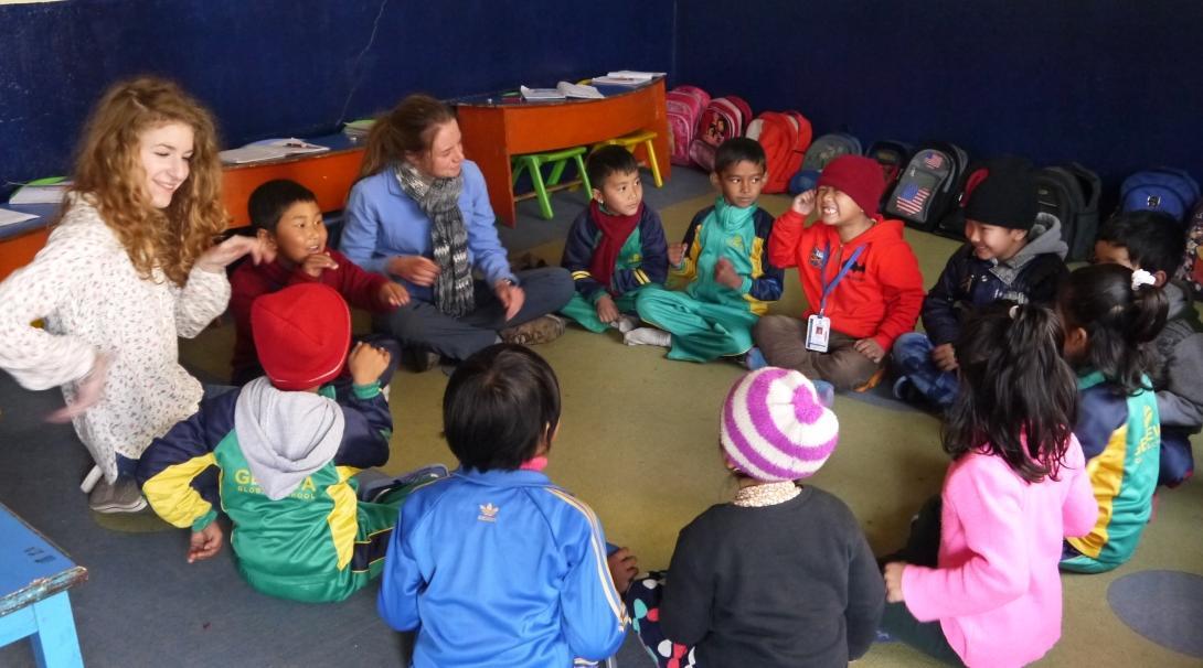 Projects Abroad Childcare volunteers in Nepal sit down with children and play educational games ar a kindergarten.