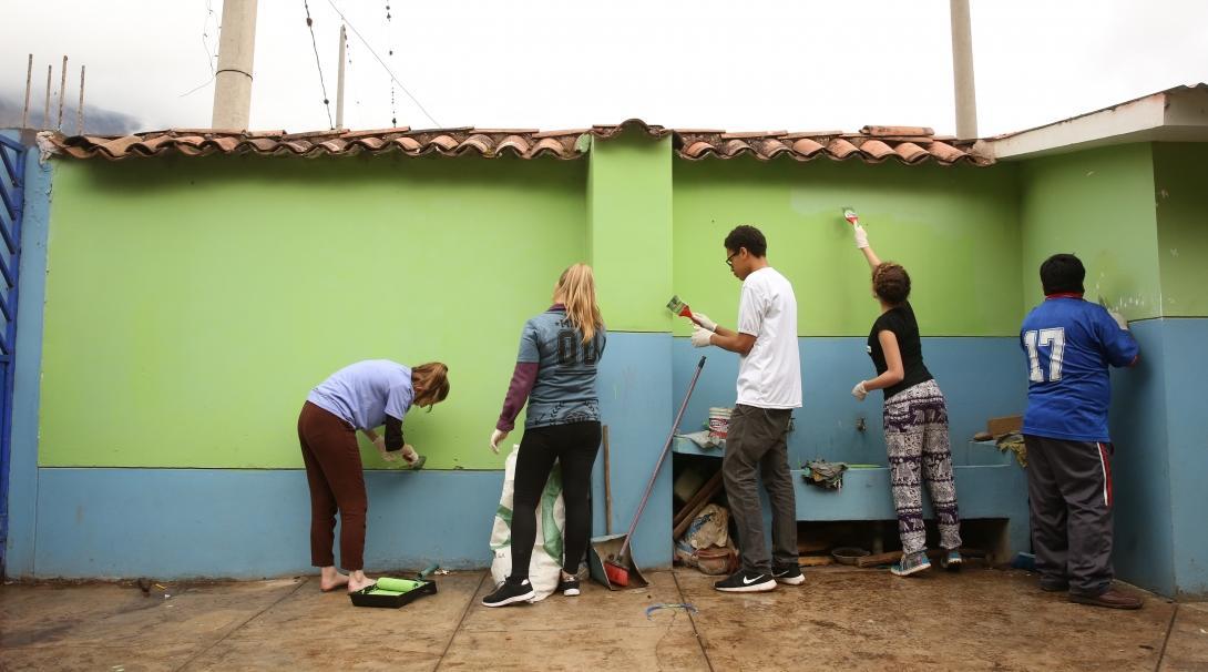 A group of Projects Abroad volunteers working with children in Peru paint a school to help enhance the learning environment.