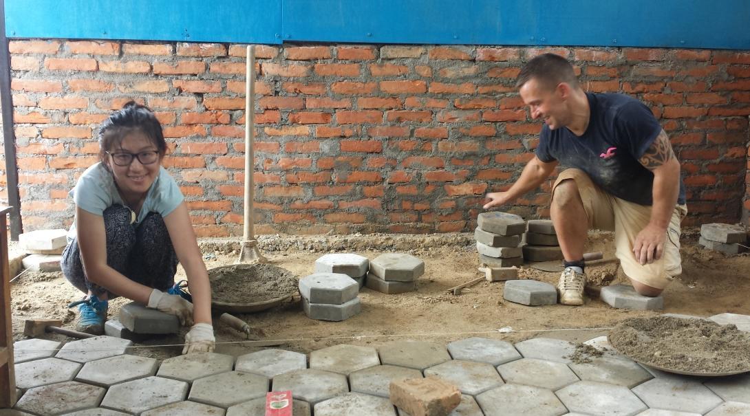 Projects Abroad volunteers assist in laying concrete slabs whilst on their building volunteer work in Nepal.