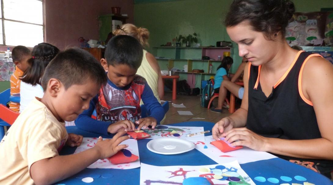 Female Projects Abroad volunteer with children in Ecuador is doing crafts during Childcare Project.