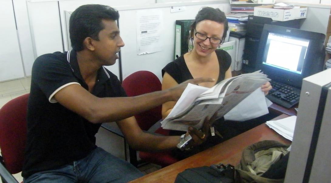 A Projects Abroad intern at her business placement in Sri Lanka checks the day's newspaper with local staff. 