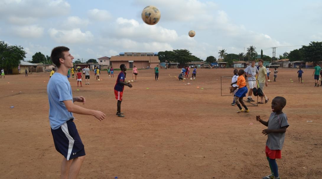 Projects Abroad volunteers taking part in football coaching for high school students in Ghana lead a ball skills practice session with a young team.  