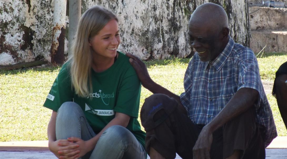 Projects Abroad Care volunteer speaks to a local man within the Community Outreach Day during Psychology placements in Jamaica.