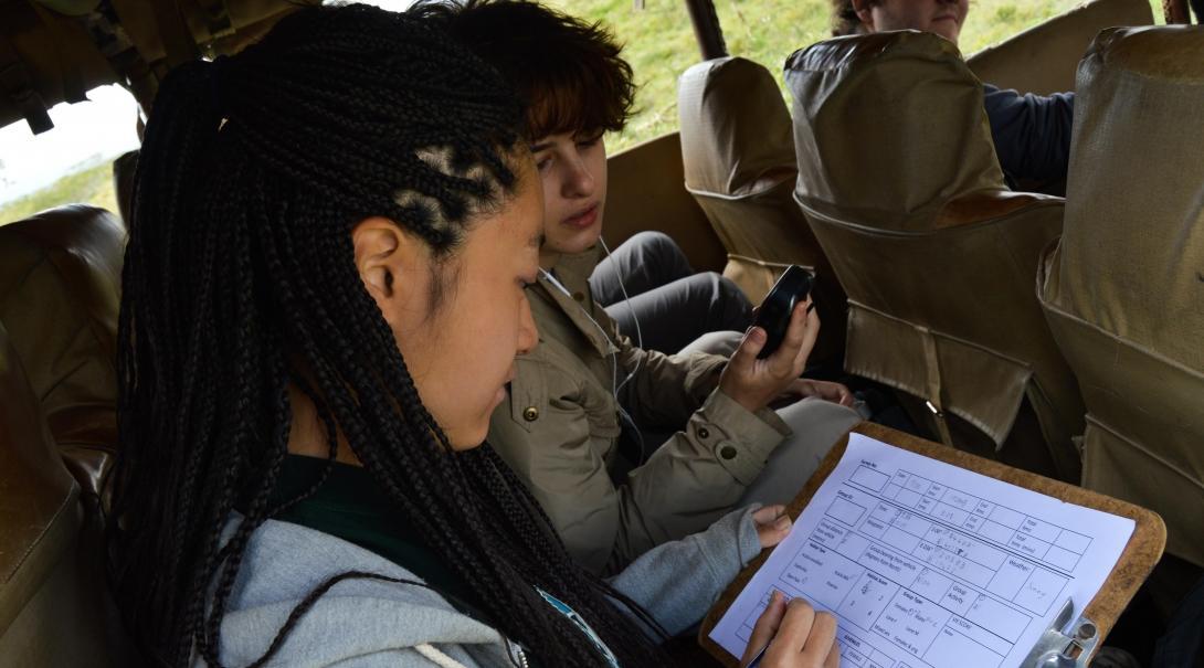 Teenagers fill in data about wildlife during conservation volunteer work in Kenya