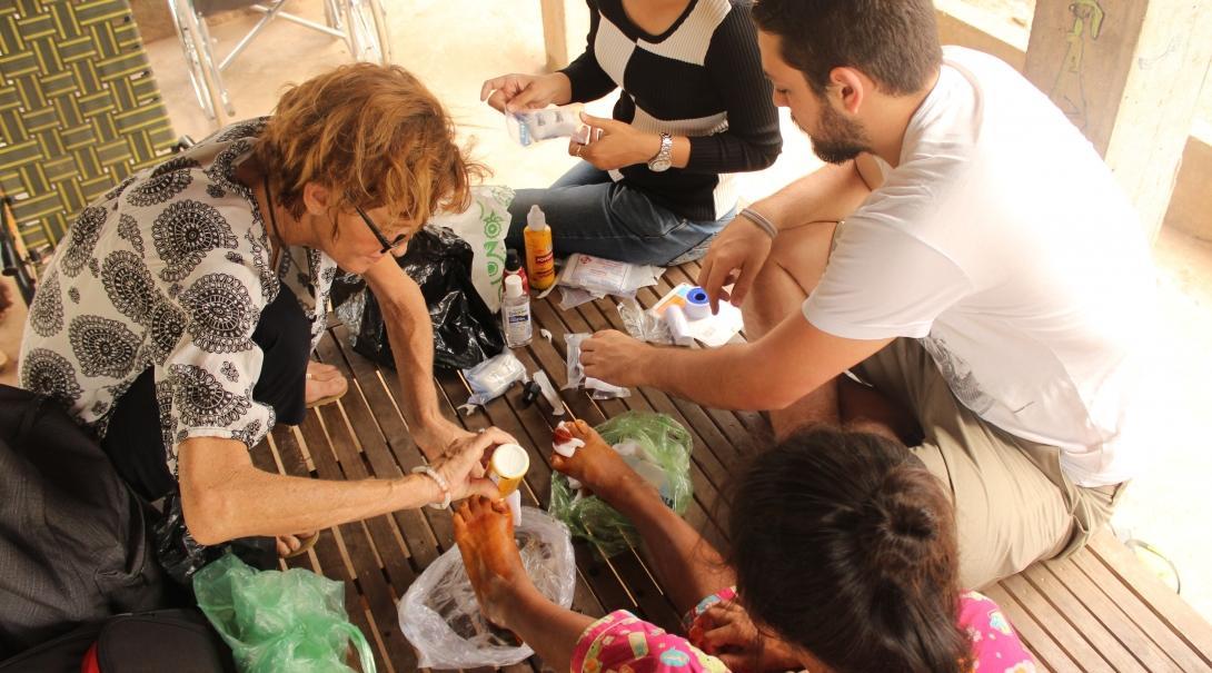 A Cambodian woman has her foot treated by Projects Abroad Medicine interns at an outreach. 