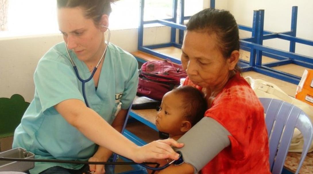 Cambodian woman and child are treated by a female intern on a medical outreach programme.
