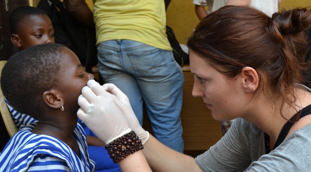 Female Medical intern treats a young patients mouth during a Medical Outreach placement in Ghana. 