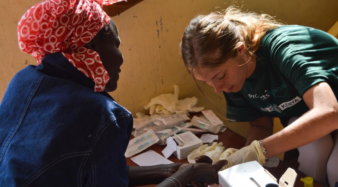 Female Medical intern treats a hand wound on a local woman during a Medical Outreach programme in Kenya.