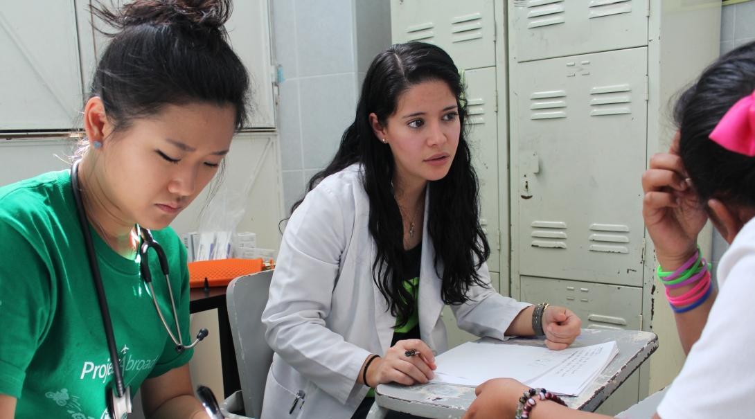 Female Medical Interns make notes on paper with a local doctor during their internship in Mexico. 