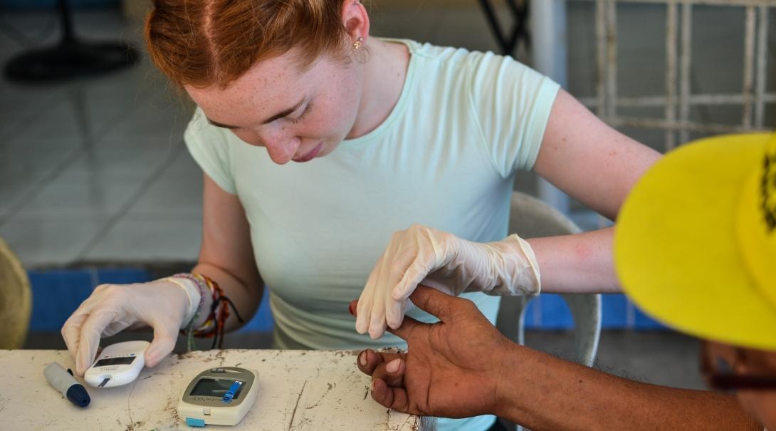 A female Projects Abroad intern during an outreach is taking blood sugar levels of various patients whilst on her medical internship in the Phillippines.