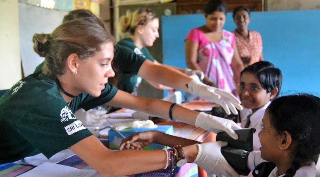A female intern takes the blood pressure of local children during her medical internship in Sri Lanka with Projects Abroad.