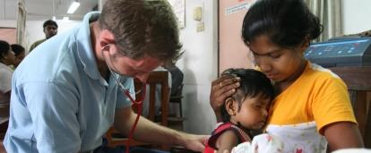 Male Projects Abroad intern giving a baby a check up whilst on his nursing internship in Sri Lanka where there are lots of nursing internship oppurtunities.