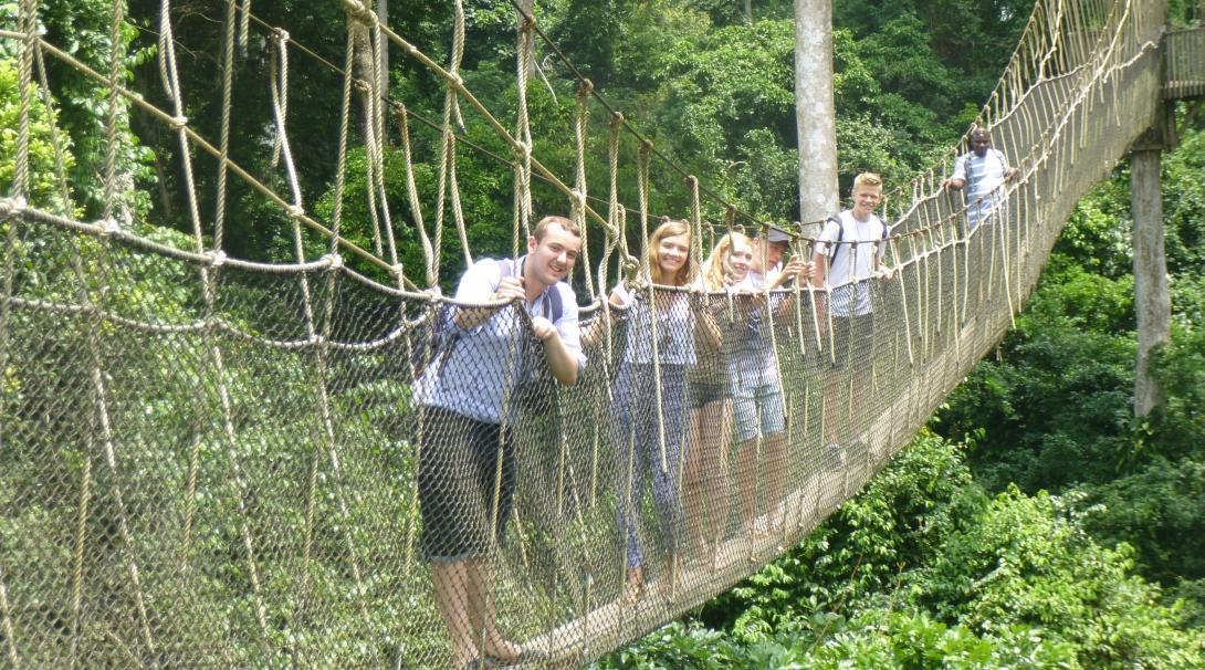 While doing community volunteer work in Ghana, teenagers use the weekends to visit local attractions like a forest walk. 