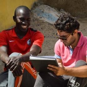 A Senegalese beneficiary discusses his business with a student doing a Micro-finance internship abroad.