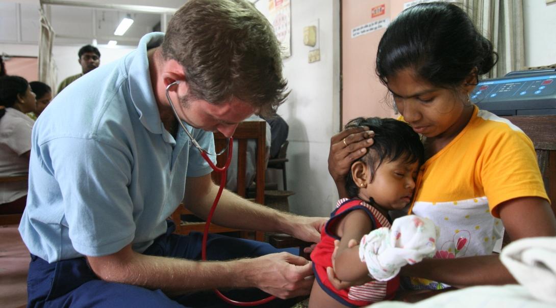 Projects Abroad male intern is seen performing a check up on a baby as part of his midwifery internship in Sri Lanka.