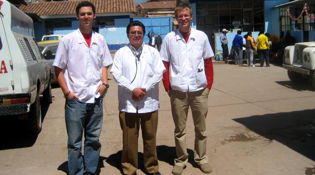 Two male interns with Projects Abroad take a picture with a local doctor outside the hospital during their nursing internship in Peru.