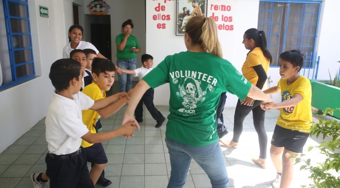 A student studying Spanish in Mexico volunteers in a local school with young children and plays educational games.  