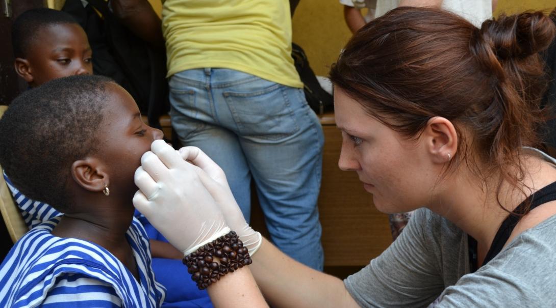 Child in Ghana is being treated on the face by a female healthcare intern at a medical outreach