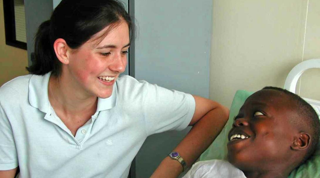 A child and a female healthcare intern are both smiling at each other in a hospital in Ghana,