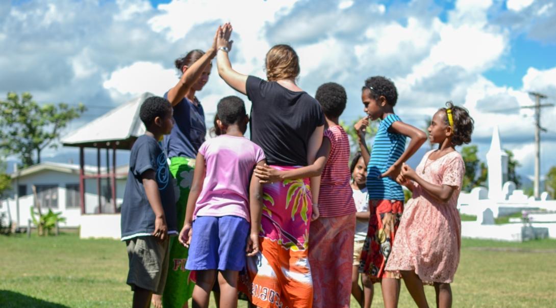 Teenagers doing volunteer work with children in Fiji lead an activity on the playground. 