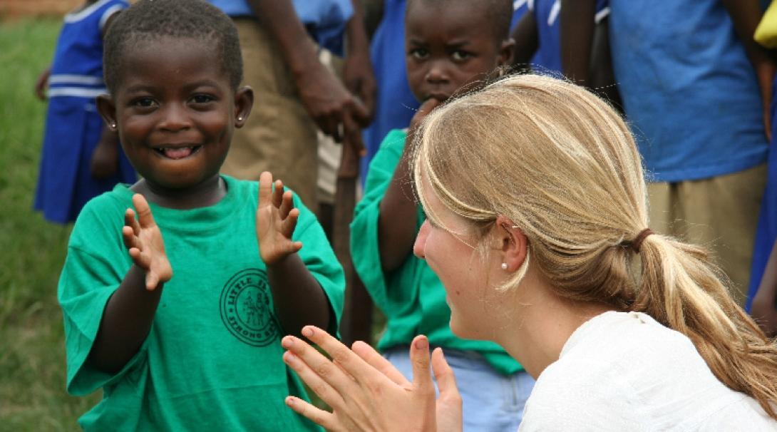 An intern and a child clap hands during an activity on our Social Work internship in Ghana