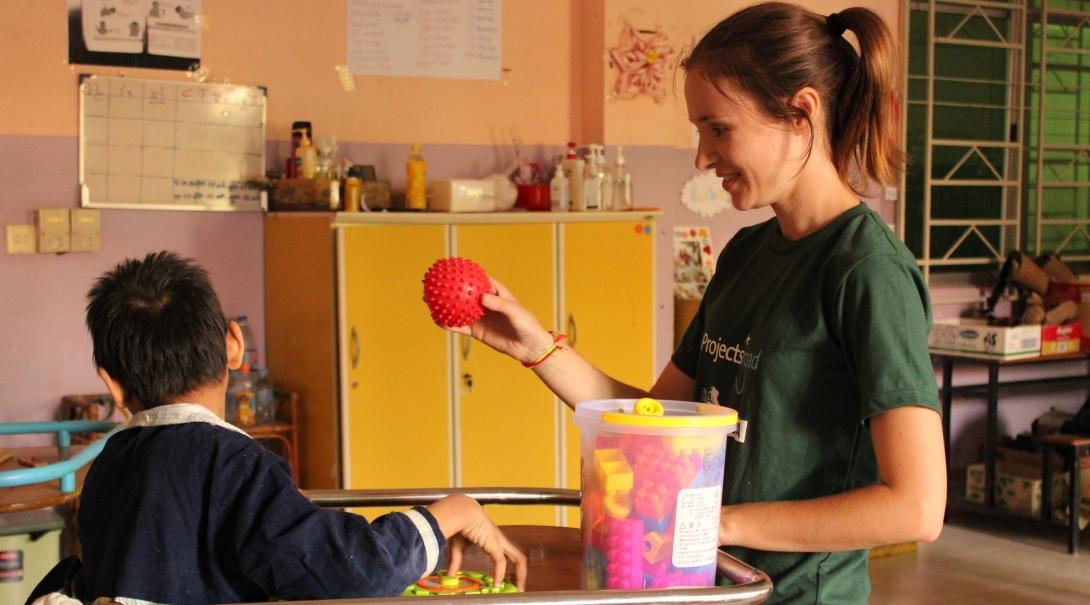 An occupational therapy internship student in Cambodia is pictured playing and engaging with a young child during her work experience with Projects Abroad.