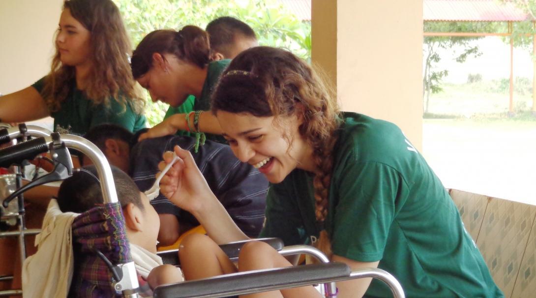 A female Projects Abroad intern is seen helping a child eat as part of her occupational therapy internship in Cambodia.