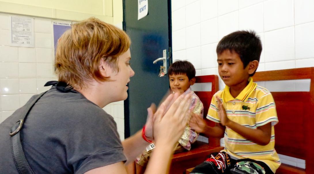 A female intern from projects Abroad can be seen clapping with a child during her occupational therapy internship in Cambodia.