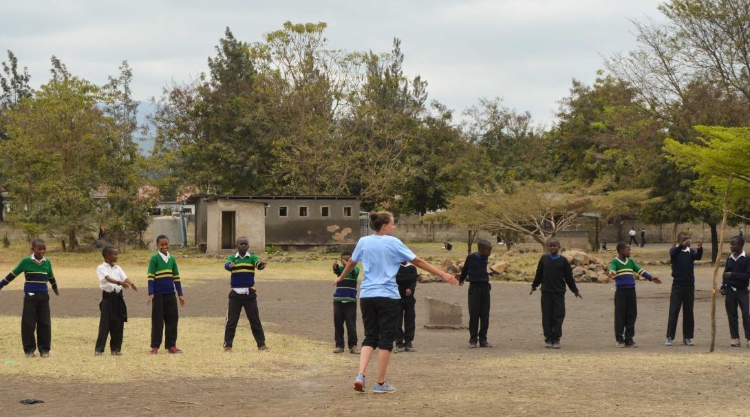 A sports instructor does a quick warm up with students during her volunteer sports coaching in schools in Tanzania