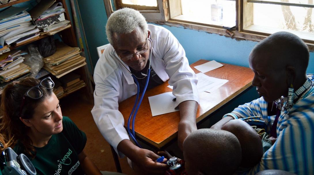 A student doing a Dentistry internship in Tanzania observes a local doctor as he performs a health check for a child. 