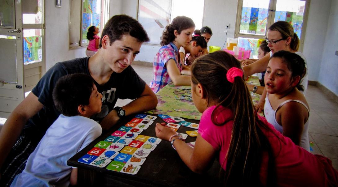 A teacher uses flashcards to help his student learn the alphabet during his teaching work experience in Argentina