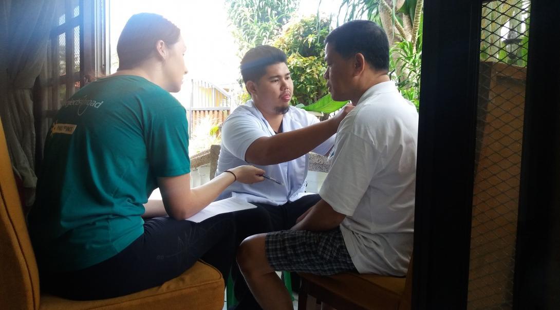 Interns are pictured helping a man exercise his shoulder whilst they complete their occupational therapy internship in the Philippines.