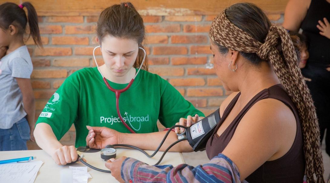 At her Projects Abroad Public Health placement for teenagers in Mexico, an intern checks a woman’s vital signs. 