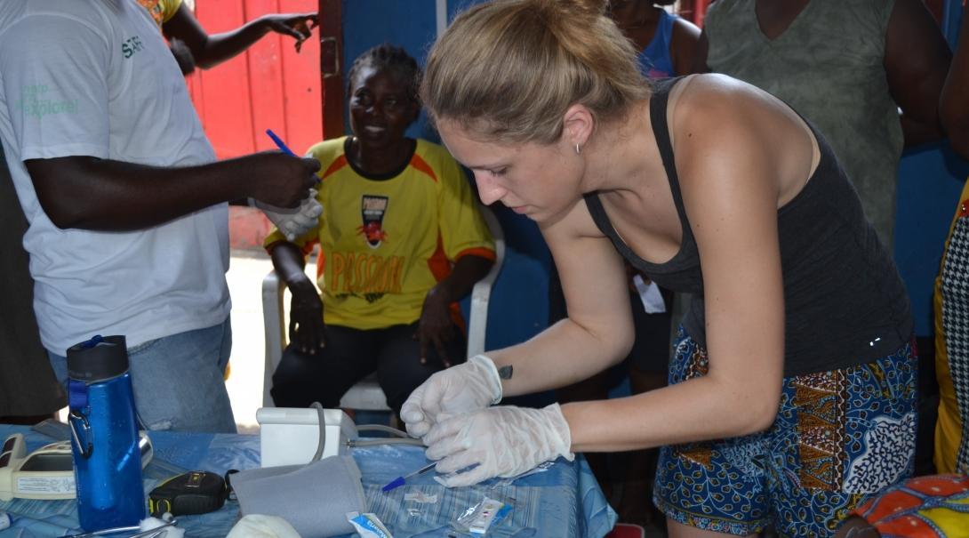 A medical outreach intern from Projects Abroad assisting in health check ups as part of her public health internship in Ghana.