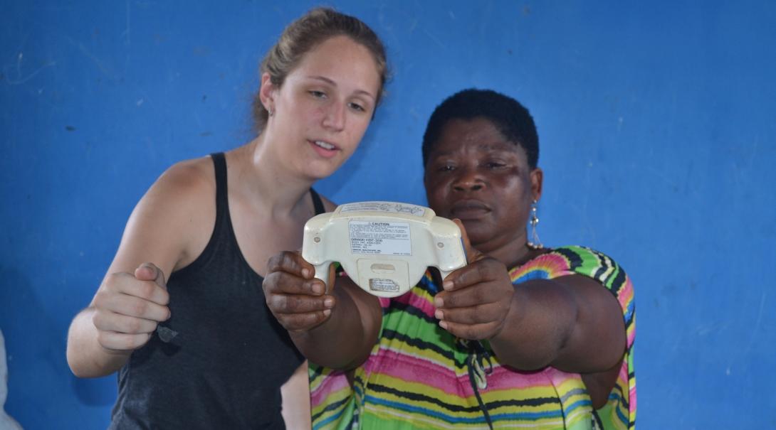 Projects Abroad intern helping a woman at a medical outreach with her treatment during her public health internship in Ghana.