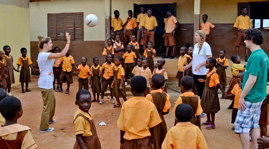 Teaching volunteers in Ghana play football in the school courtyard with their students