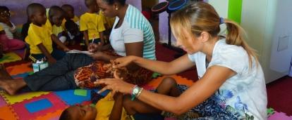 Projects Abroad Intern doing stretches with local children during her occupational therapy internship in Tanzania.
