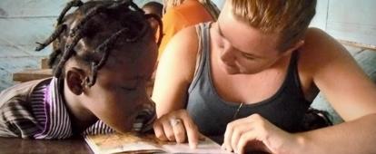 An intern is seen helping a young girl learn how to read and pronunciate whilst on her speech therapy internship in Ghana.