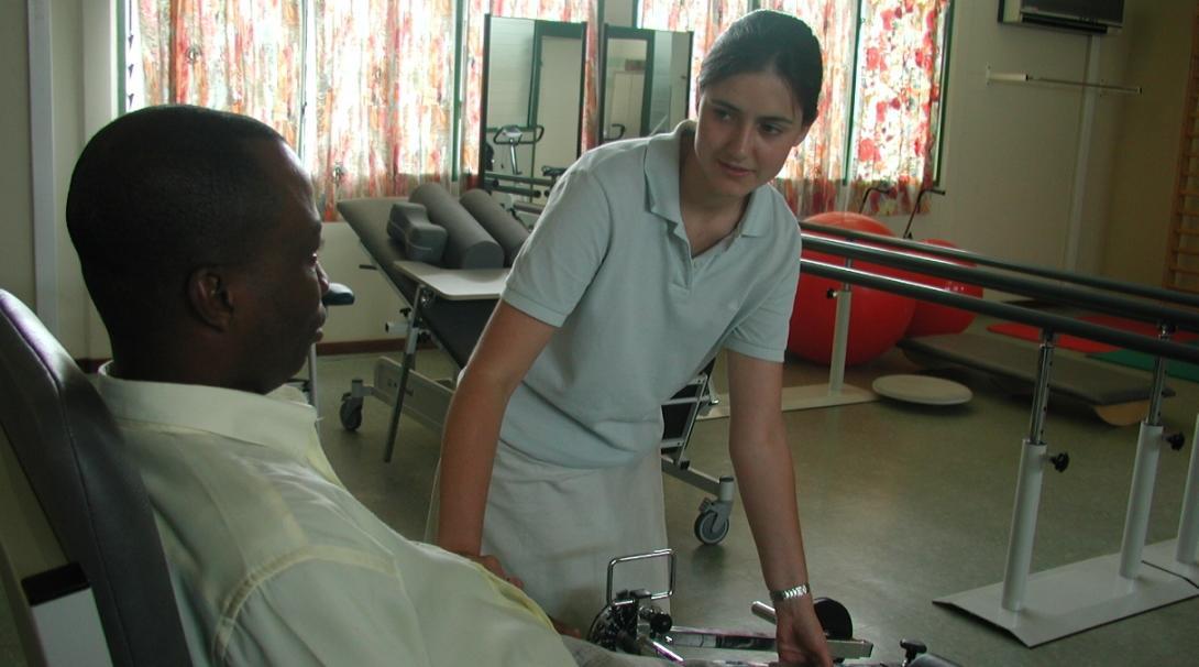 An intern from Projects Abroad is pictured helping a man stretch as part of her physiotherapy internship in Ghana.