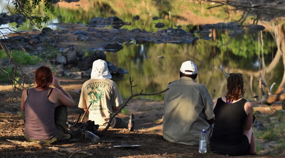 A couple of interns taking in the scenery overlooking a lake whilst taking part in a census activity on their wildlife conservation volunteering project in Botswana with Projects Abroad.