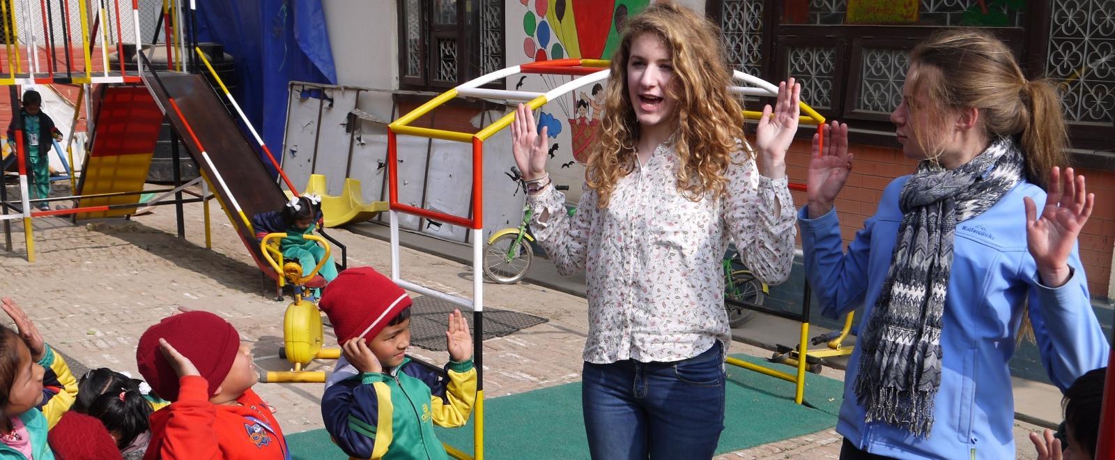 Teenage volunteers doing work with children in Nepal, do an activity with children on the playground.  
