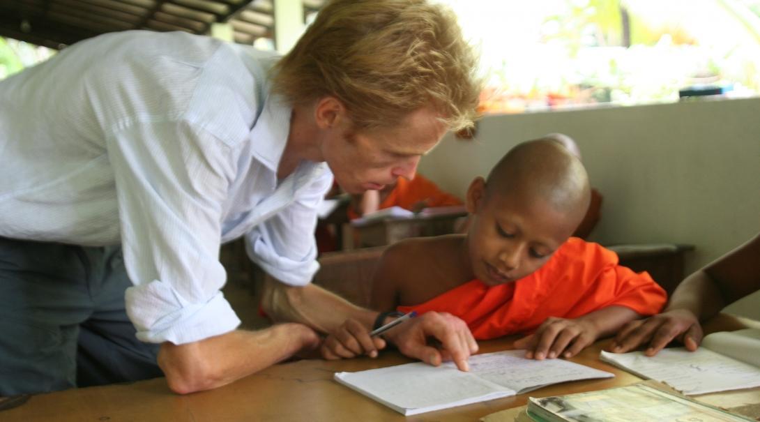 A young monk receives help from a volunteer teaching English in Sri Lanka